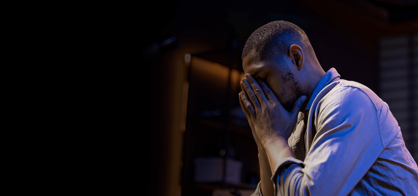 Man in visible distress with his hands over his face
