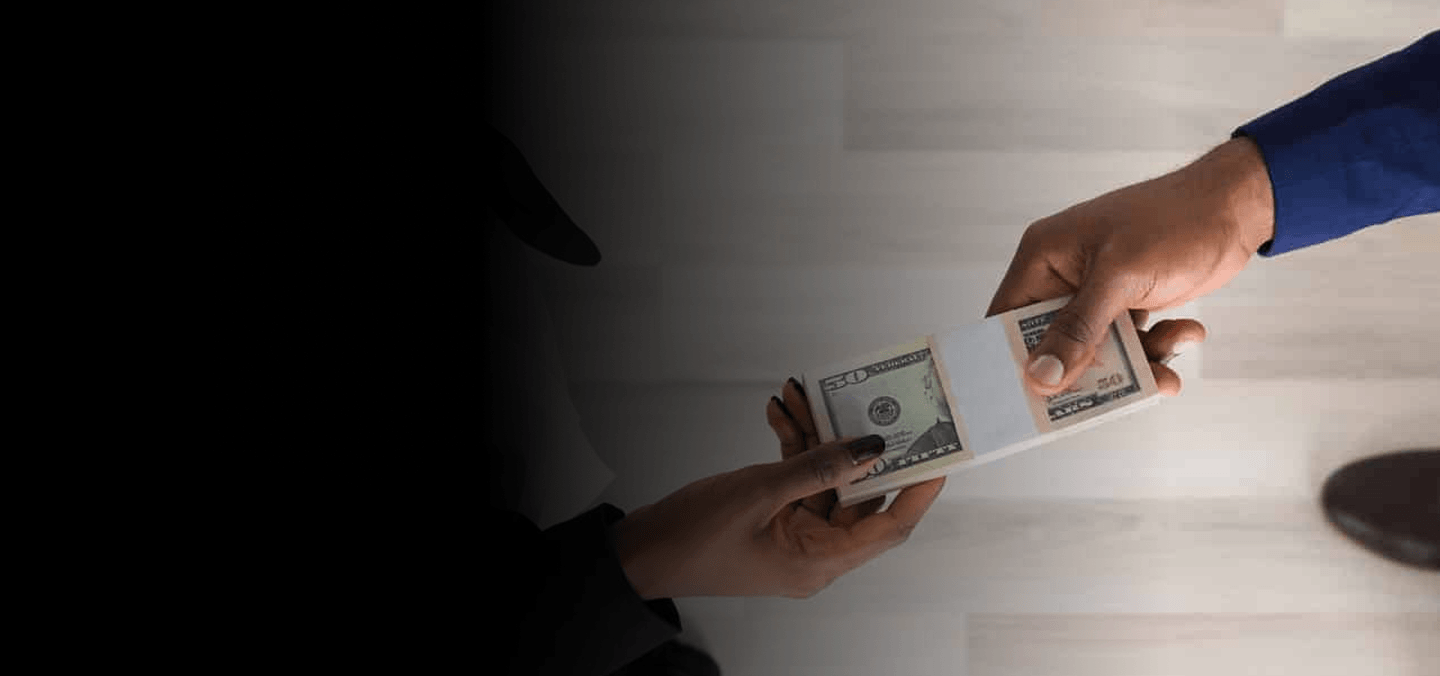 Hand passing cash to another person across a desk