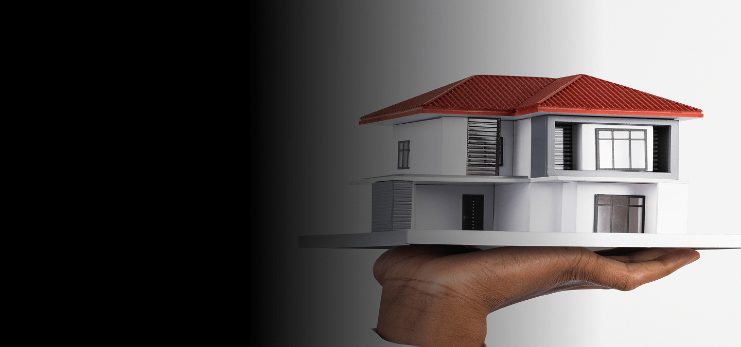 Hand holding a model house with a red roof