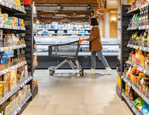 Shopper pushing a cart through a grocery store aisle