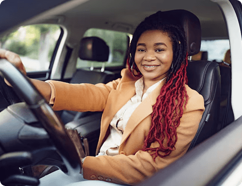 Smiling woman sitting behind the wheel of her car