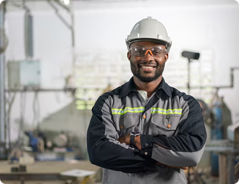 Engineer in a hard hat and safety glasses standing confidently in a workshop