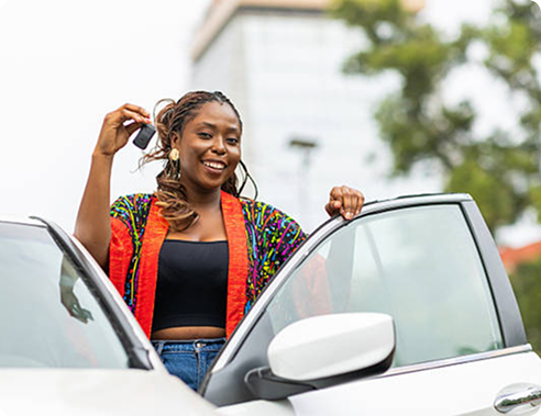 Woman smiling while stepping out of her car with keys in hand